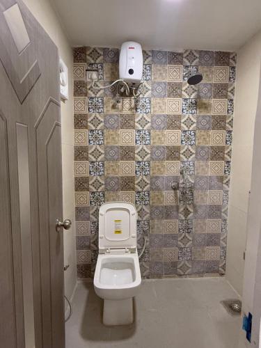 a bathroom with a toilet and a tiled wall at Half Orangee Party Stay with Free Swimming Pool, Free Game Room, Free Parking Next to Vagator Beach-Near to Chapora Fort-Near to Hill Top -Best for Couples-Backpackers, Long stays, Coworking, Day-use with Game zone and summer vacation!! in Vagator