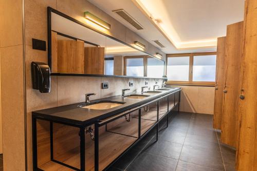 a bathroom with a row of sinks and mirrors at Camping Sass Dlacia in San Cassiano
