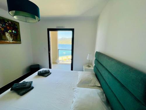 - une chambre avec un grand lit blanc et une tête de lit verte dans l'établissement Superbe T3 front de mer au centre de Propriano, à Propriano