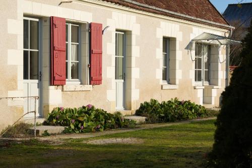 a house with red shutters and flowers in the yard at Le gîte de la Roche in Chenonceaux