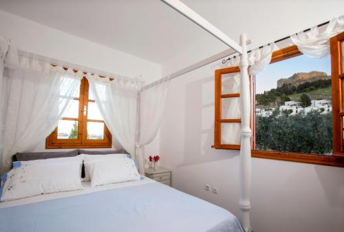 a white bedroom with a bed and a window at Lindos Seaside Villa in Lindos