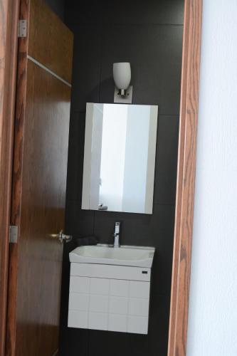 a bathroom with a sink and a mirror and a door at Suites La Gloria Alojamiento independiente in Tepatitlán de Morelos