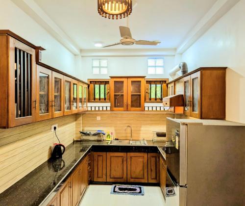 a large kitchen with wooden cabinets and a refrigerator at Halcyon Rest in Hikkaduwa