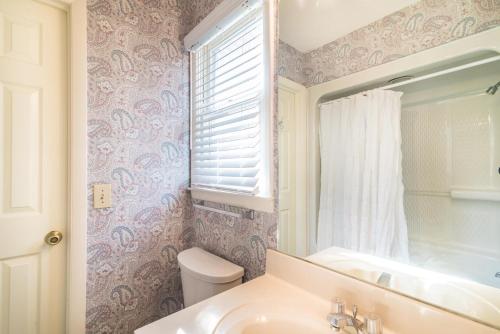 a bathroom with a sink and a toilet and a window at Cozy and Tranquil Creekfront Cottage in Litchfield in Pawleys Island
