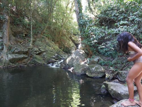 a young girl standing on rocks near a river at Suite dos pássaros in Ilhabela