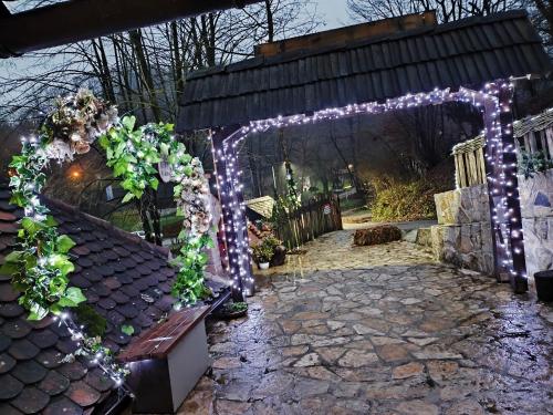 an arch with lights and a bench in a yard at Konak Lecic in TrÅ¡iÄ‡