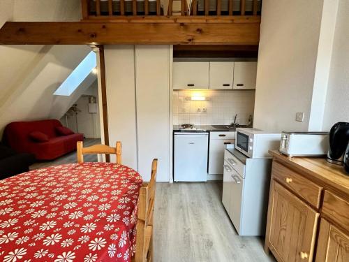 une petite cuisine avec une table et une chaise rouge dans l'établissement Résidence Face Sud - maeva Home - Studio 5 personnes - Confort MAE-1881, à La Mongie