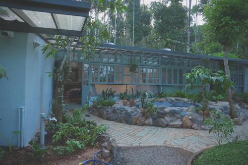 a building with a garden in front of it at Malhar - Your Home Beneath The Clouds in Sultan Bathery