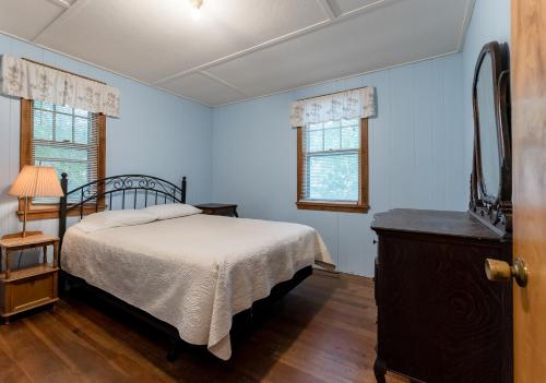 a bedroom with a bed and a dresser and two windows at Red Cottage Cute Holland cottage walk to beach in Holland