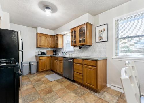 a kitchen with wooden cabinets and a black refrigerator at Private pool, close to Lake Michigan Beaches in Muskegon