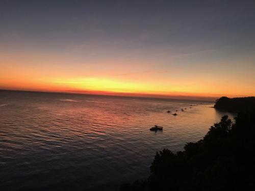 a group of boats on the water at sunset at Noor Villa - Luxury 3 Bed, 2 Bath Apartment with Stunning Panoramic Sea View, Private Beach in Pinamihagan