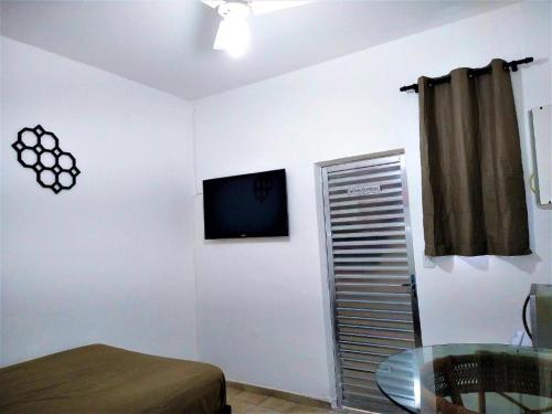 a room with a bed and a television on a wall at Hospedagem Primeira Quadra da Praia in Praia Grande