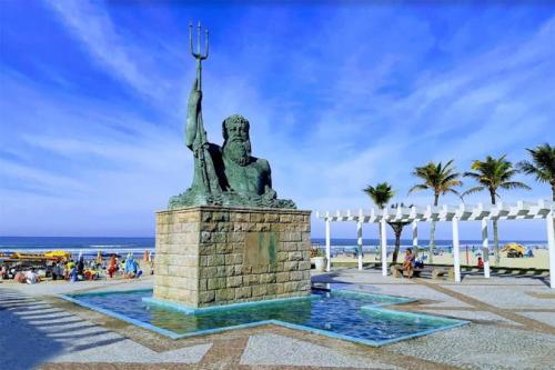a statue on the beach with the ocean in the background at Hospedagem Primeira Quadra da Praia in Praia Grande