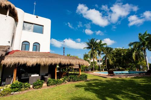 a building with a grass roof and a swimming pool at Sunset Paradise Villa at Nichupté Lagoon in Cancún