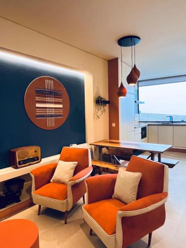a living room with orange chairs and a table at Bragança Apartments in Bragança