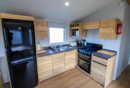 a small kitchen with a black refrigerator and wooden cabinets at MP303 Parkdean Camber Sands in Camber