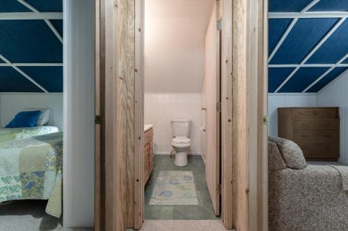 a bathroom with a toilet and a bedroom with blue ceilings at Experience the charm of Silver Lake at Parrothead Retreat in Mears