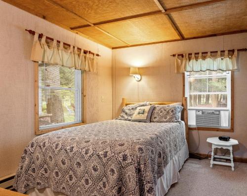 a bedroom with a bed and two windows at Experience the charm of Silver Lake at Parrothead Retreat in Mears
