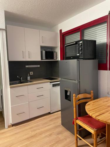 une cuisine avec une table et un réfrigérateur en acier inoxydable dans l'établissement Jolie T2 en plein centre-ville ville de Font-Romeu, à Font-Romeu-Odeillo-Via