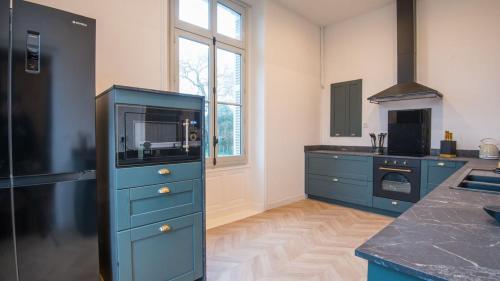 une cuisine avec un meuble bleu avec un micro-ondes dans l'établissement l'écrin du lac, à Angers
