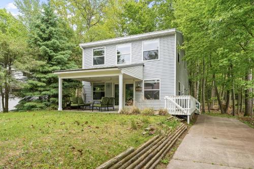 a white house with a porch in the trees at Greenwood Beach House - beach access and a variety of outdoor activities. in Mears