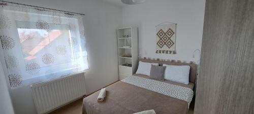a small bedroom with a bed and a window at Aqua apartmanház Gyenesdiás in Gyenesdiás