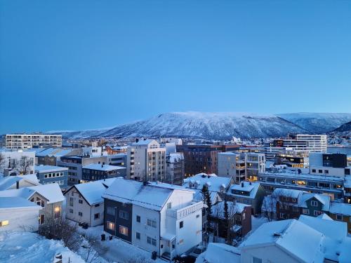 een stad bedekt met sneeuw met bergen op de achtergrond bij Apartment in Tromsø City Centre in Tromsø