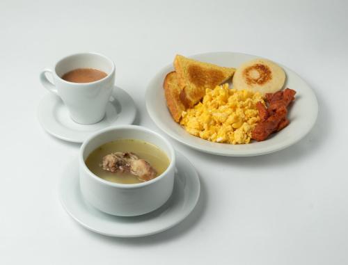 two cups of coffee and a plate of breakfast foods at Hotel ByHours Las Américas in Bogotá