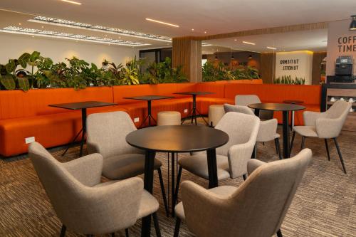 a waiting room with tables and chairs and plants at Hotel ByHours Las Américas in Bogotá