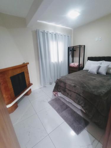 a bedroom with a bed and a television in it at Cantinho na serra in Monte Verde