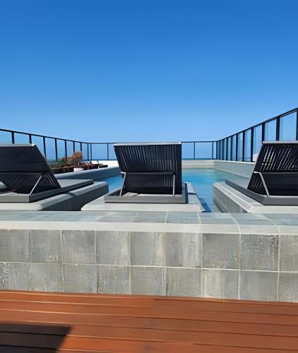 a swimming pool with three benches on a building at Get By Side in João Pessoa