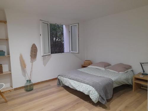 une chambre blanche avec un lit et deux fenêtres dans l'établissement La marjolaine, à Aubagne