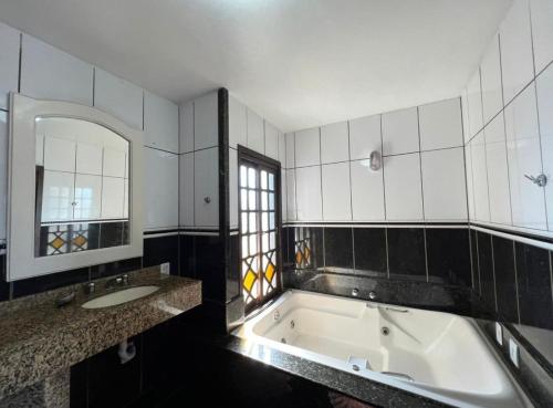 a bathroom with a tub and a sink and a mirror at Pousada Bella Praia in Torres