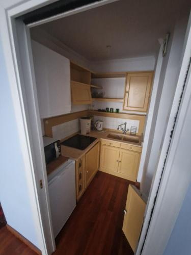 Elle comprend une petite cuisine avec des placards en bois et un évier. dans l'établissement Top Floor Astoria vista Mare, à Menton