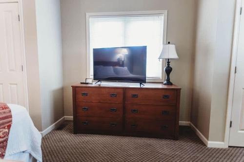 a television on a dresser in a bedroom with a window at Picturesque Condo perfect for Golf, Families, Pools and Lake vacation in Bellaire