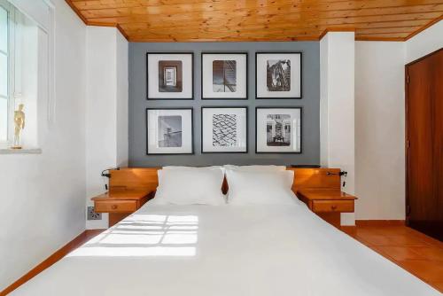 - une chambre dotée d'un grand lit blanc avec des photos sur le mur dans l'établissement Casa do Farol - Charming Townhouse, à Lagos