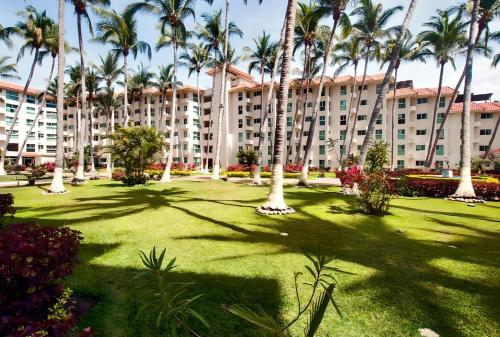 a large building with palm trees in a park at Marina Suites by Andiani Travel in Bucerías