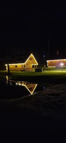 a building is lit up at night with lights at Mana Village - Jacuzzi & Sauna in Barłomino