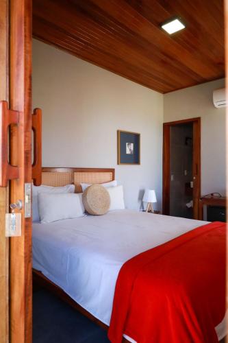 a bedroom with a white bed with a red blanket at Lyttos Bungalows in Icapuí