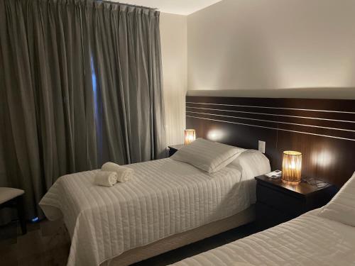 Una habitación de hotel con dos camas y dos lámparas. en Achalay Colonia Dora Hotel Boutique, en Colonia Dora
