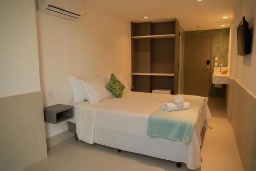 a bedroom with a large white bed with a table at Arraial Concept Hotel in Arraial do Cabo