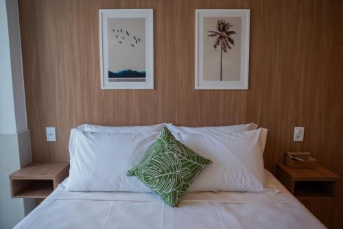 a bed with white pillows and two pictures on the wall at Arraial Concept Hotel in Arraial do Cabo