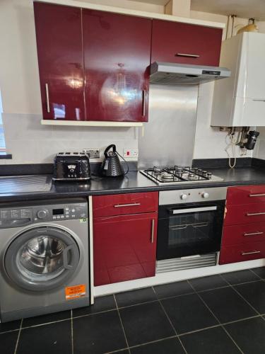 a kitchen with red cabinets and a washing machine at Lux Den close to M1! Netflix , Parking & Broadband in Milton Keynes