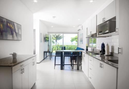 a kitchen with white cabinets and a table in it at Beachfront Condo - your Oasis with pool and Wi-Fi in Bejuco