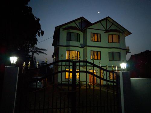 a large house with a gate in front of it at night at Pine Haven Resorts in Takdāh