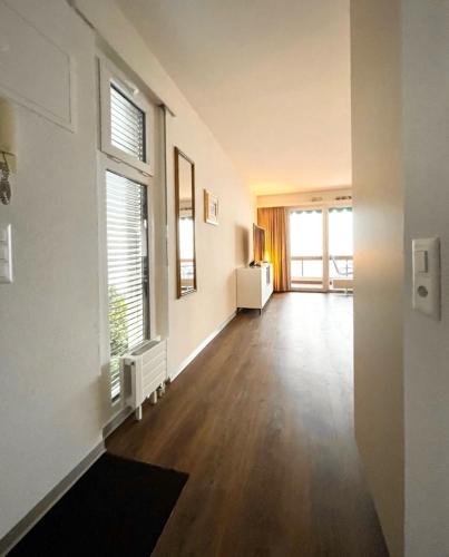 an empty living room with a hard wood floor and windows at Ferienwohnung D27 in Orselina