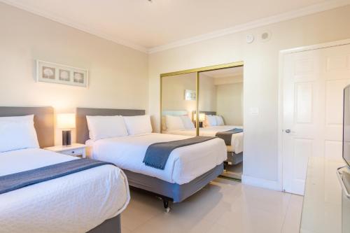 a hotel room with two beds and a mirror at Golden Bay 406 in Miami Beach