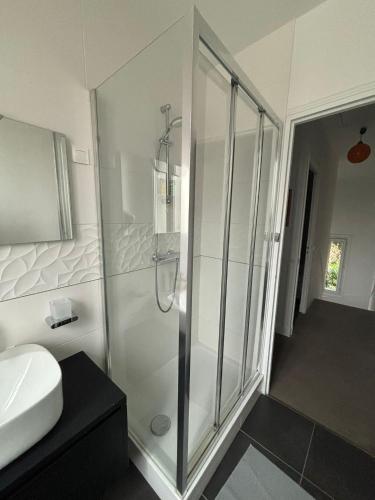 une salle de bain blanche avec une douche et un lavabo dans l'établissement Agréable Maison Familiale, à Arcueil