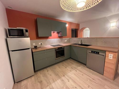 a kitchen with green cabinets and a white refrigerator at Naturel loft 5 personnes et jardin in Saint-Maurice-sur-Moselle