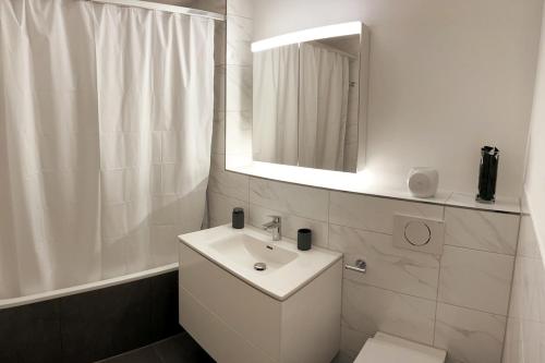 a white bathroom with a sink and a mirror at Furnished apartment Davos Platz close to WEF in Davos